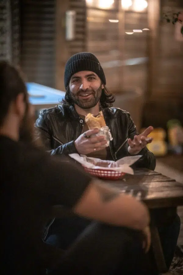 man eating a burrito with his friend