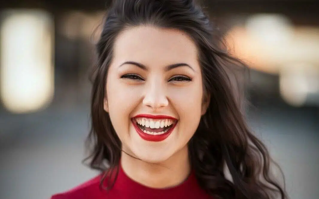 A girl in a red sweater laughing loudly